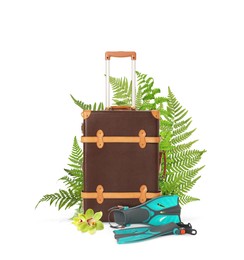 Brown travel suitcase, swim fins, tropical leaves and flower on white background