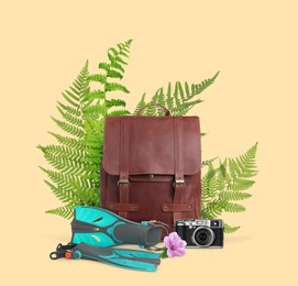 Image of Leather backpack, camera, swim fins, tropical leaves and flower on beige background. Time to travel