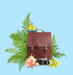 Image of Leather backpack, sea stars, seashells, camera, toy sailboat, tropical leaves and flowers on light blue background. Time to travel