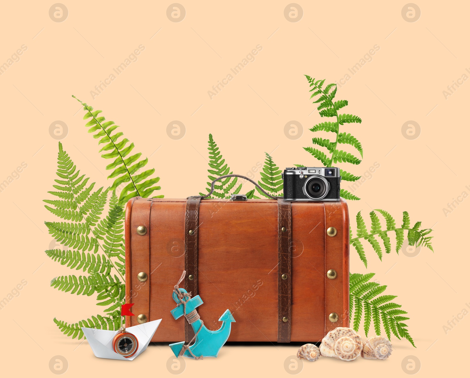 Image of Brown travel suitcase, tropical leaves, seashells, camera, paper boat and toy anchor on pink beige background