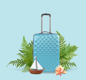 Image of Light blue travel suitcase, tropical leaves, sea star, seashells and toy sailboat on color background