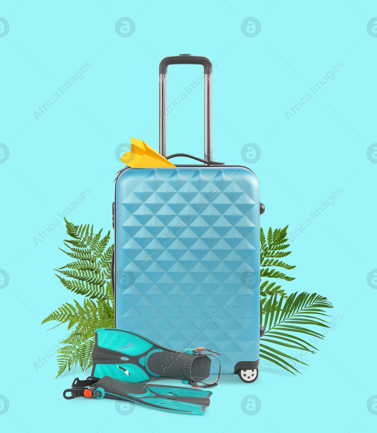 Image of Light blue travel suitcase, tropical leaves, paper plane and swim fins on cyan color background