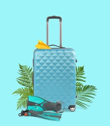 Image of Light blue travel suitcase, tropical leaves, paper plane and swim fins on cyan color background