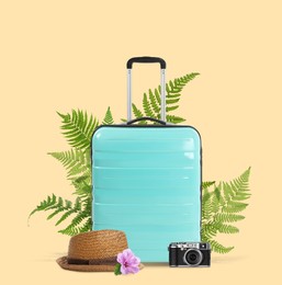 Image of Turquoise travel suitcase, camera, hat, tropical leaves and flower on beige background