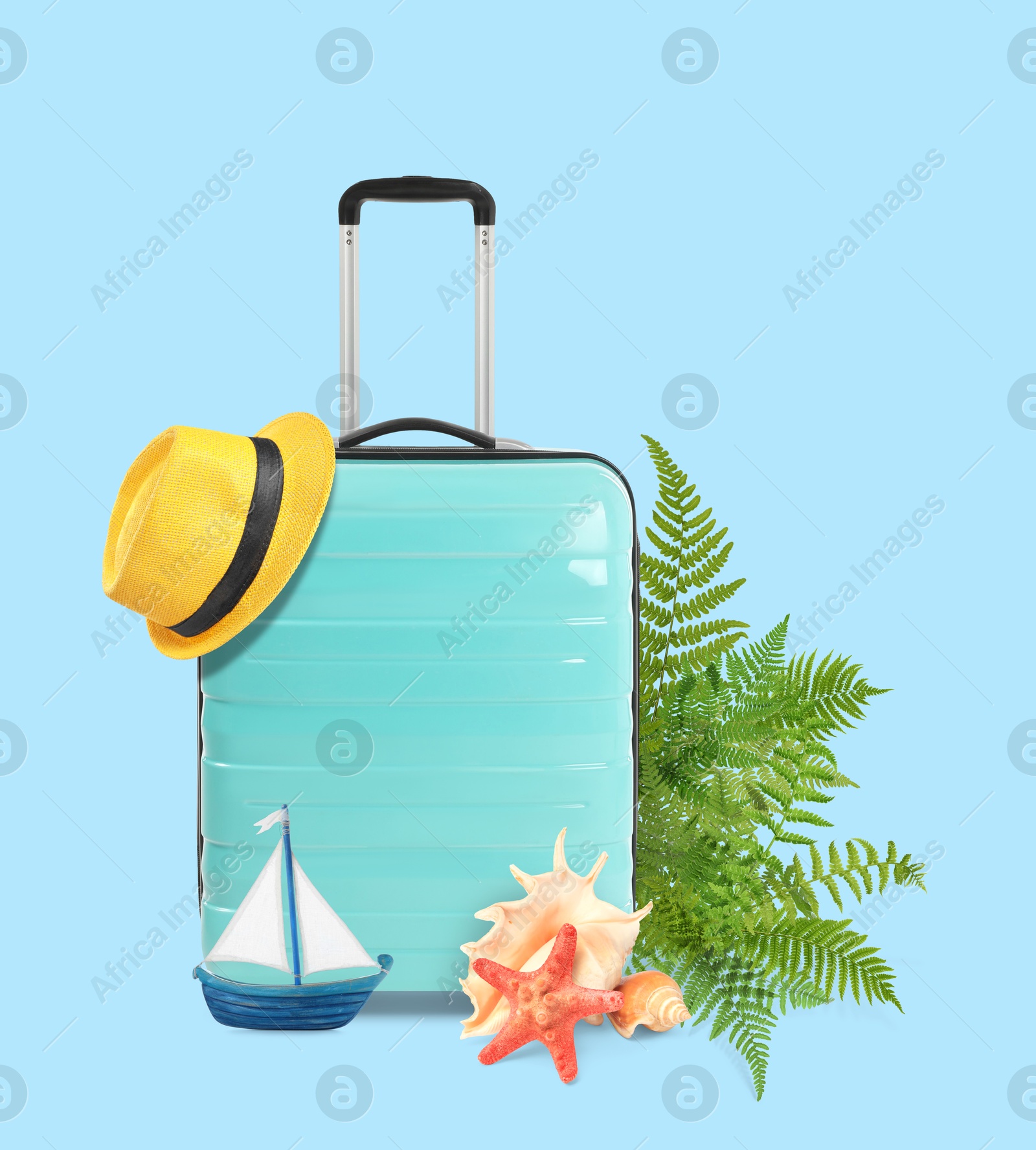 Image of Turquoise travel suitcase, tropical leaves, hat, sea star, seashells and toy sailboat on light blue background