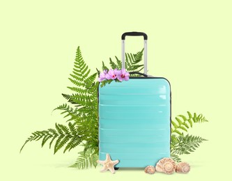 Image of Turquoise travel suitcase, seashells, sea star, tropical leaves and flowers on light green background