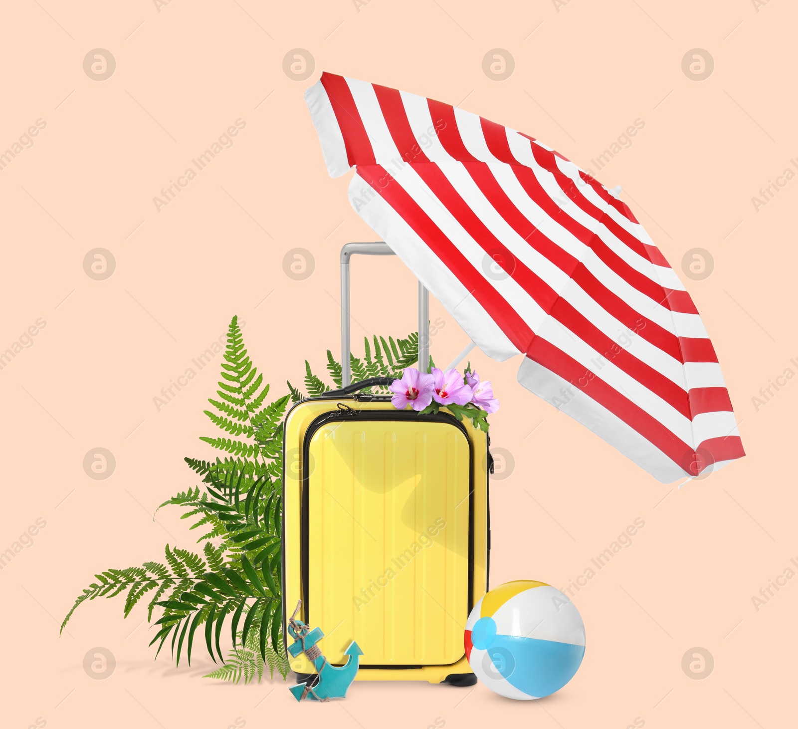 Image of Yellow travel suitcase, beach umbrella and ball, toy anchor, tropical leaves and flowers on pink beige background