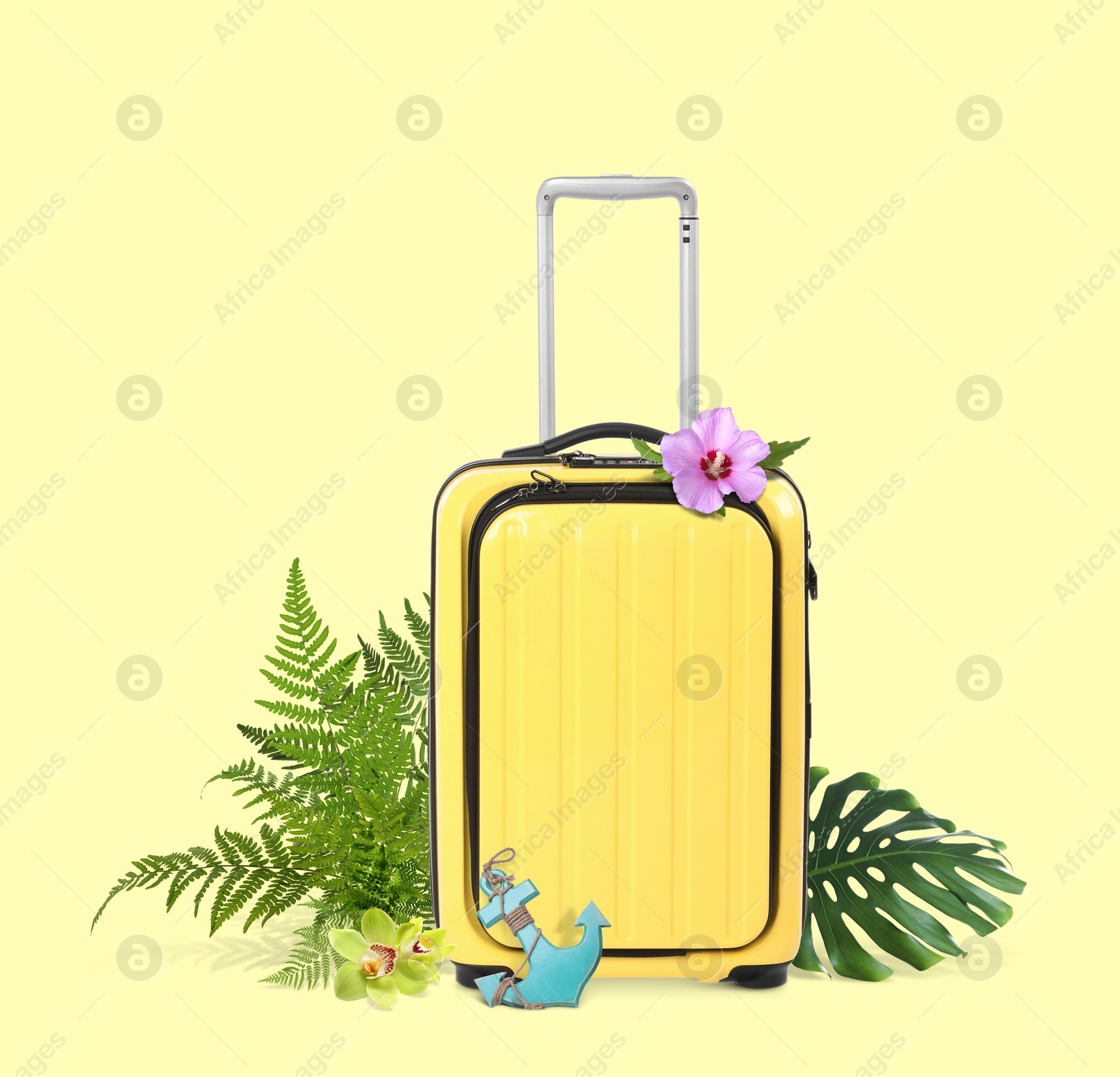 Image of Yellow travel suitcase, toy anchor, tropical leaves and flowers on color background