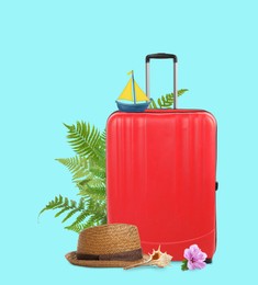 Image of Red travel suitcase, toy sailboat, hat, seashell, tropical leaves and flower on cyan color background