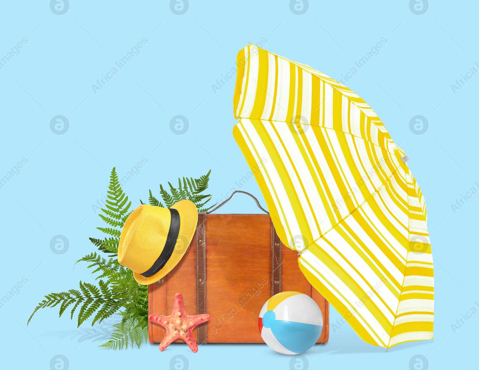 Image of Brown travel suitcase, tropical leaves, beach umbrella and ball, hat and sea star on light blue background