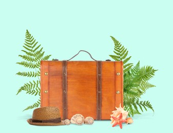 Brown travel suitcase, tropical leaves, hat, sea star and seashells on light blue background