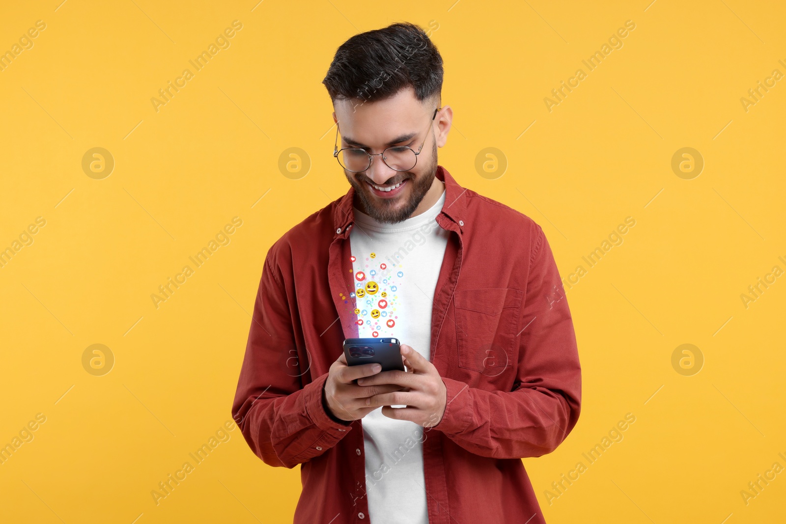 Image of Happy man using mobile phone on orange background. Different notification signs over gadget