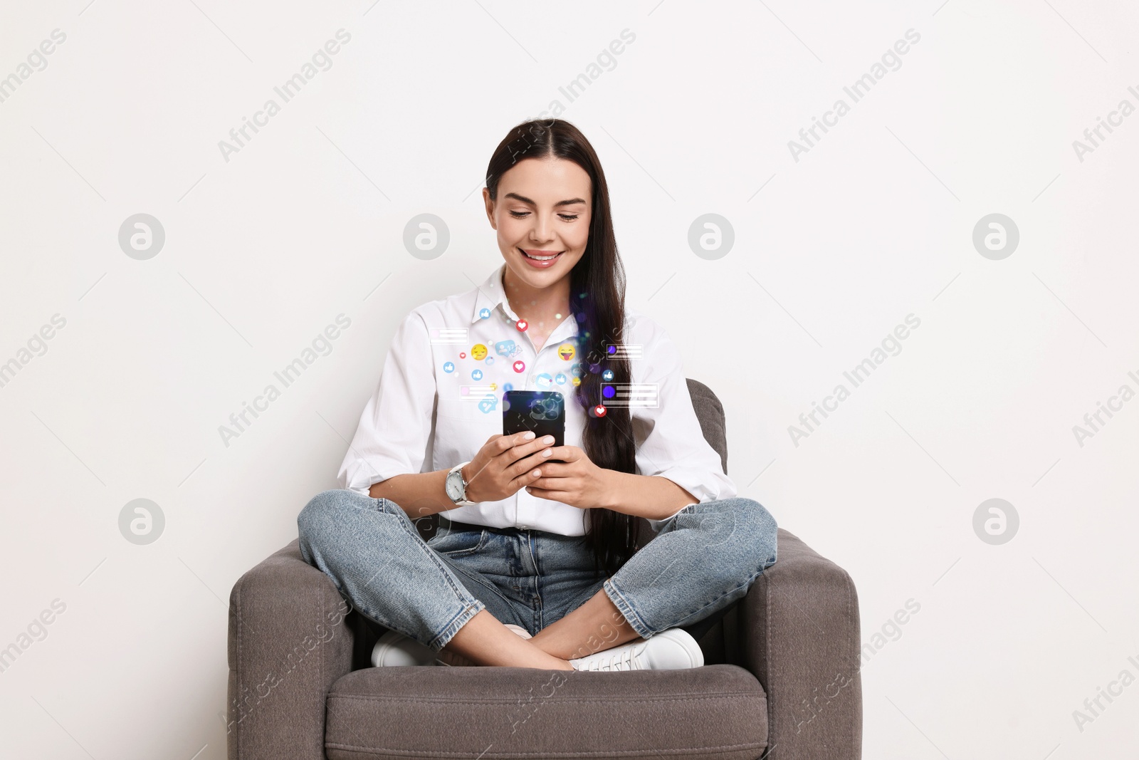 Image of Happy woman using mobile phone while sitting in armchair on white background. Different notification signs over gadget