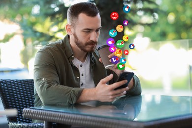 Image of Man using mobile phone while drinking beverage at outdoor cafe. New message sign and other notifications over gadget