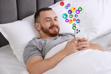 Happy man using mobile phone in bed at home. New message sign and other notifications over gadget