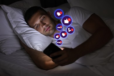 Image of Man using mobile phone in bed at night. Different notification signs over gadget