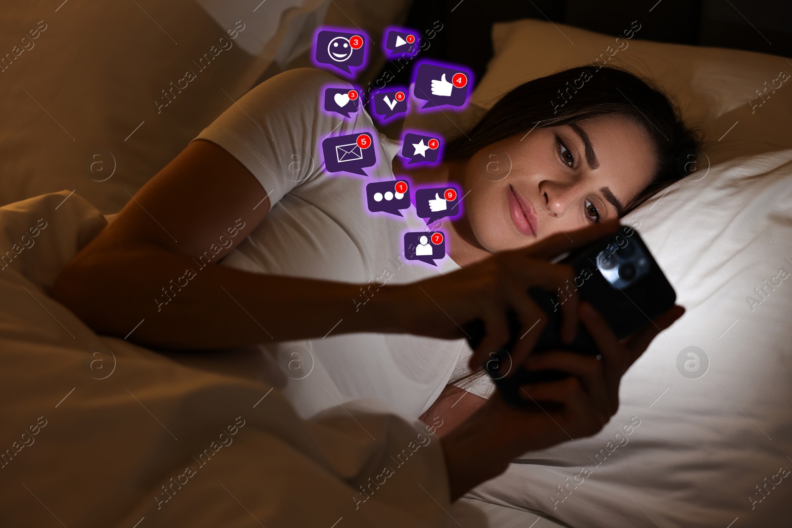 Image of Woman using mobile phone in bed at night. New message sign and other notifications over gadget