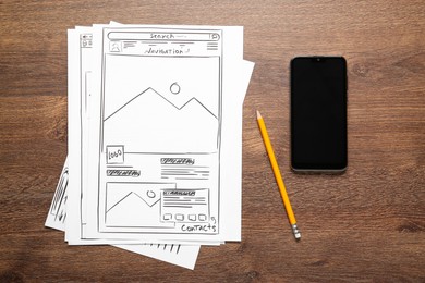 Photo of Developing UI design. Sketches of website wireframes, pencil and smartphone on wooden table, top view