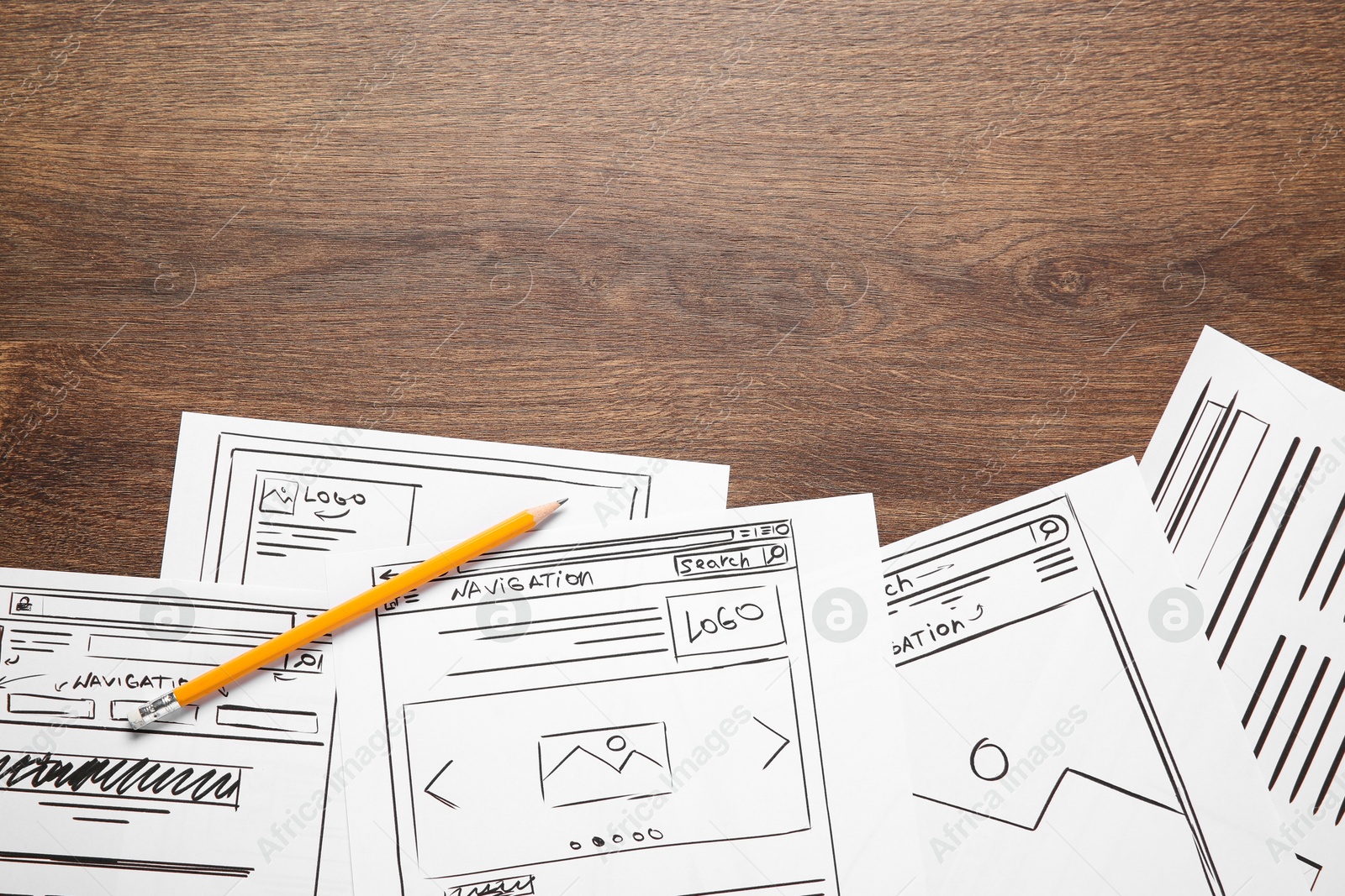 Photo of Developing UI design. Sketches of website wireframes and pencil on wooden table, top view