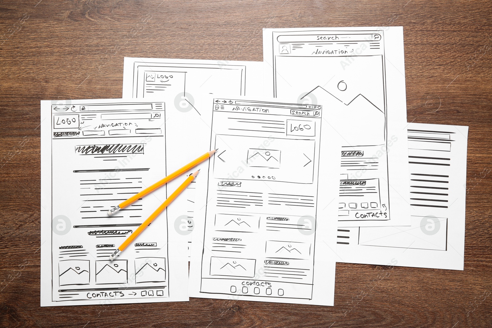 Photo of Developing UI design. Sketches of website wireframes and pencils on wooden table, top view