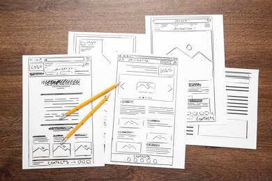 Photo of Developing UI design. Sketches of website wireframes and pencils on wooden table, top view