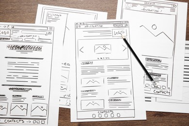 Photo of Developing UI design. Sketches of website wireframes and pencil on wooden table, top view