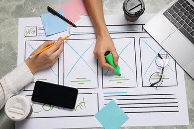 Photo of Developing UI design. Designers creating website wireframe on paper at grey marble table, top view