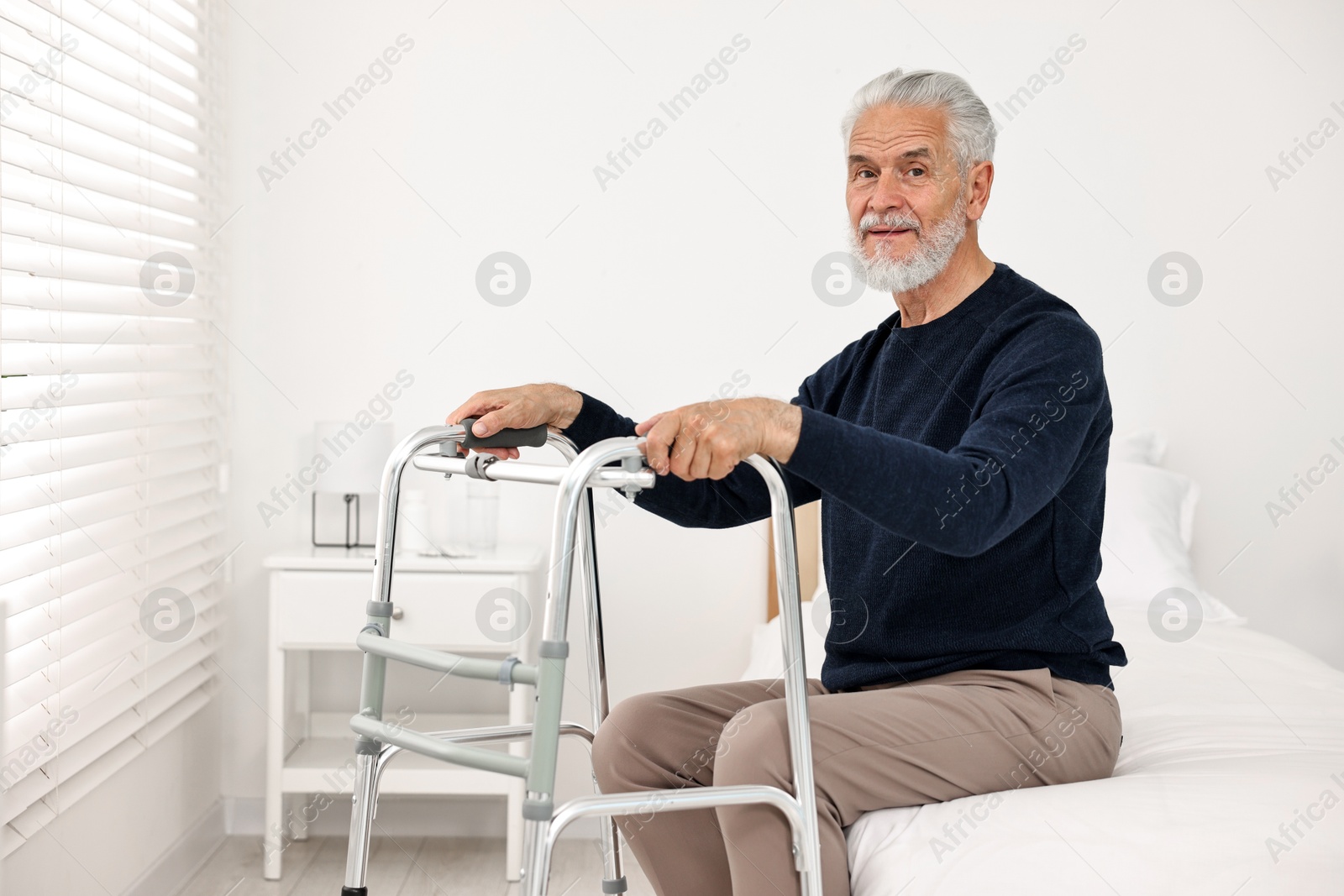 Photo of Senior man with walking frame on bed in hospital ward