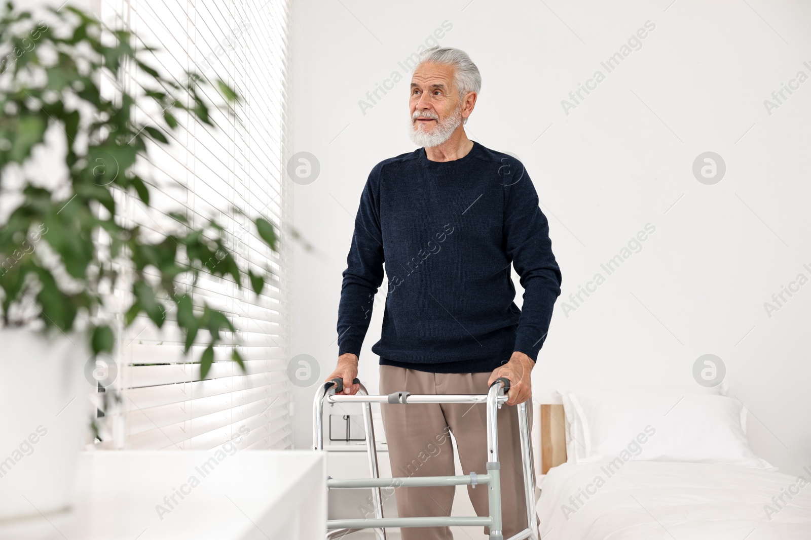 Photo of Senior man with walking frame in hospital ward