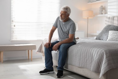 Photo of Lonely senior man sitting on bed at home