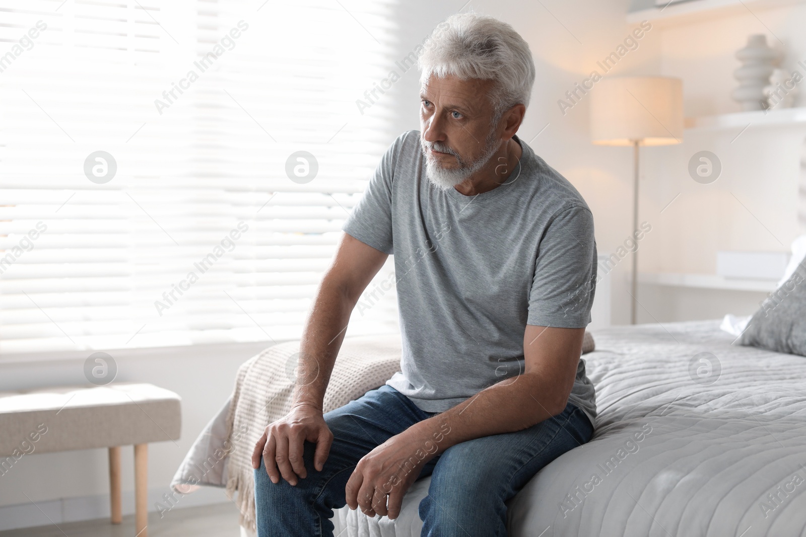 Photo of Lonely senior man sitting on bed at home