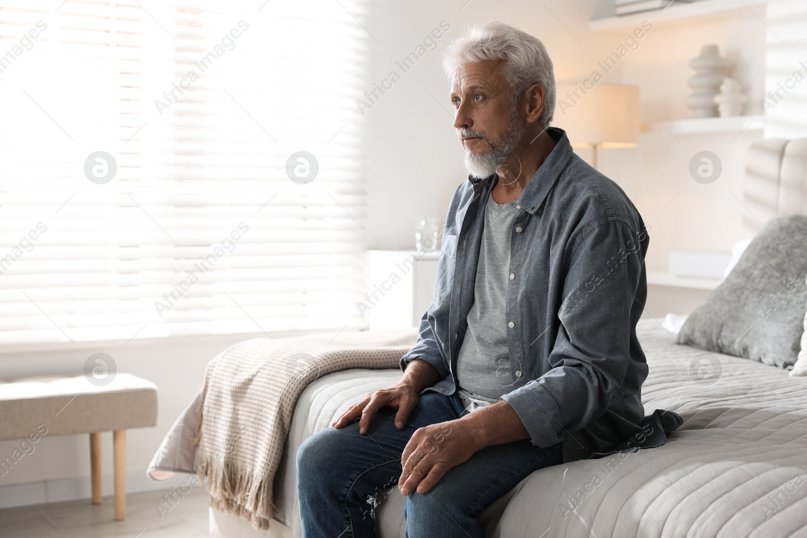 Photo of Lonely senior man sitting on bed at home