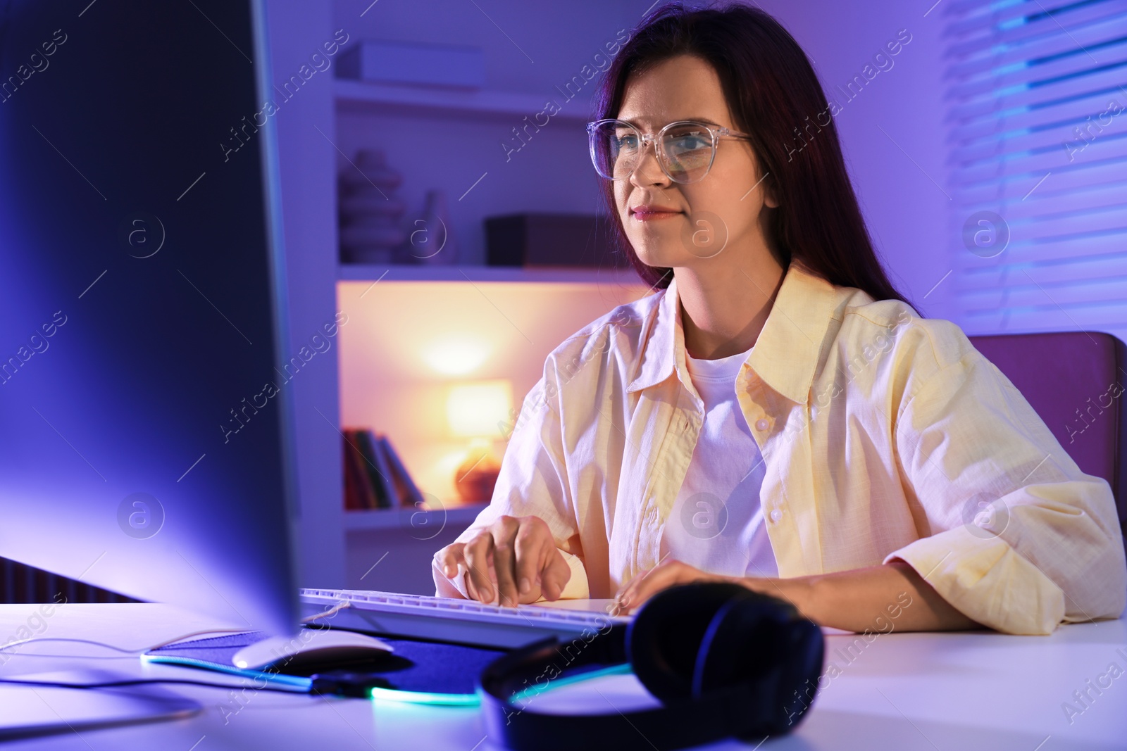 Photo of Woman playing video game with keyboard at table indoors