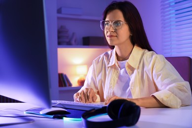 Woman playing video game with keyboard at table indoors