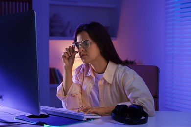 Woman playing video game with keyboard at table indoors