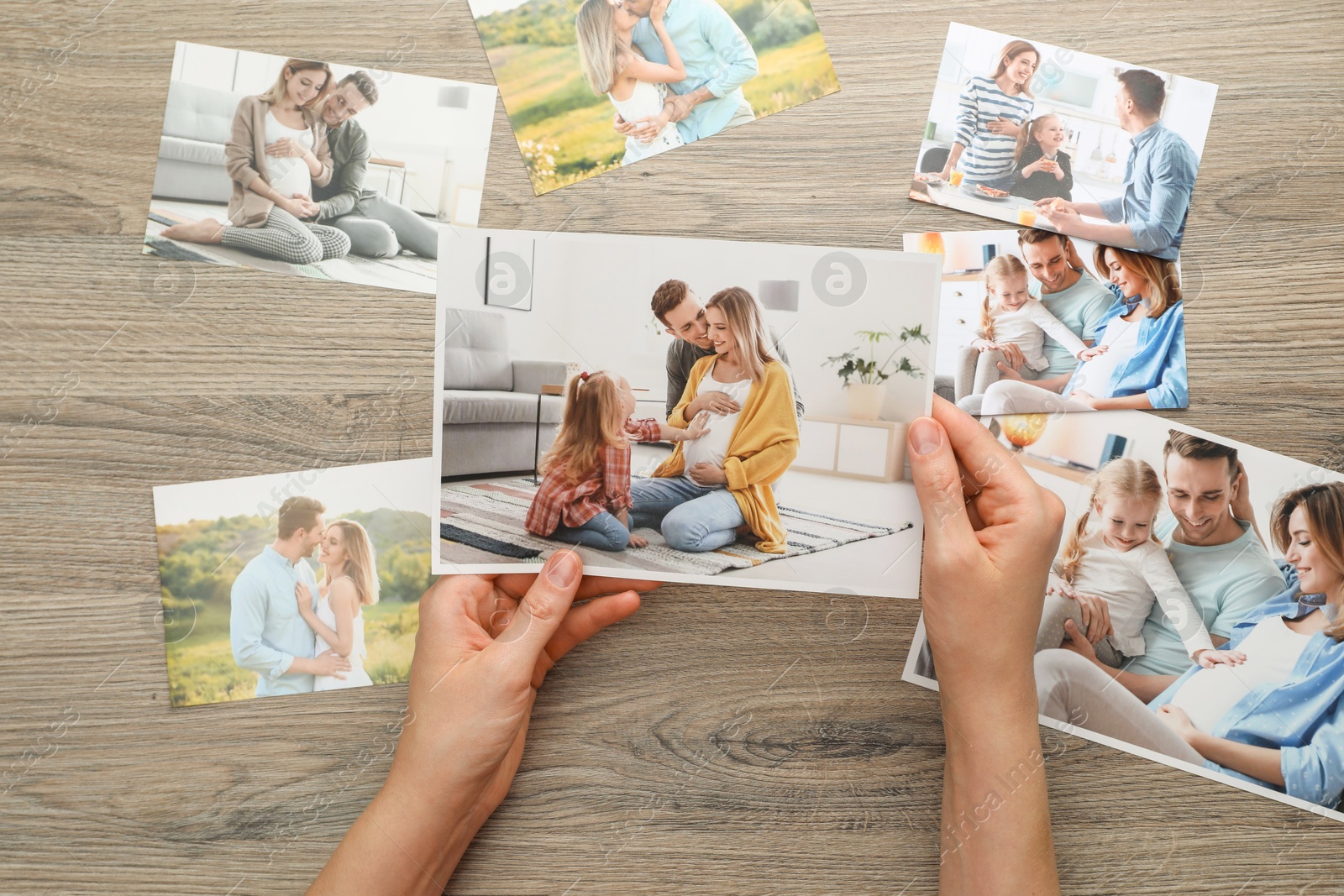 Photo of Woman with different photos at wooden table, top view