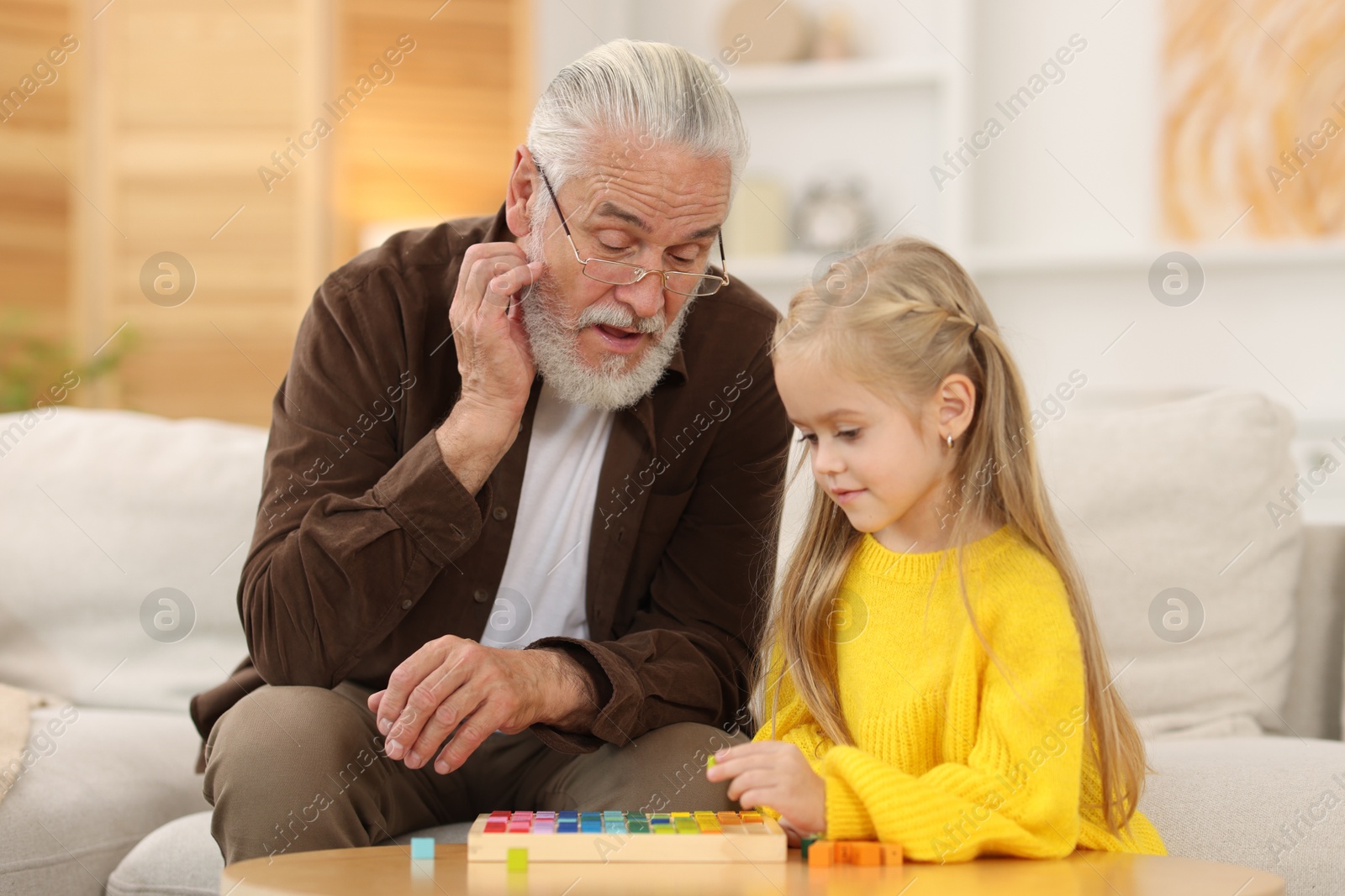 Photo of Grandpa and his granddaughter playing with math game Times table tray at home