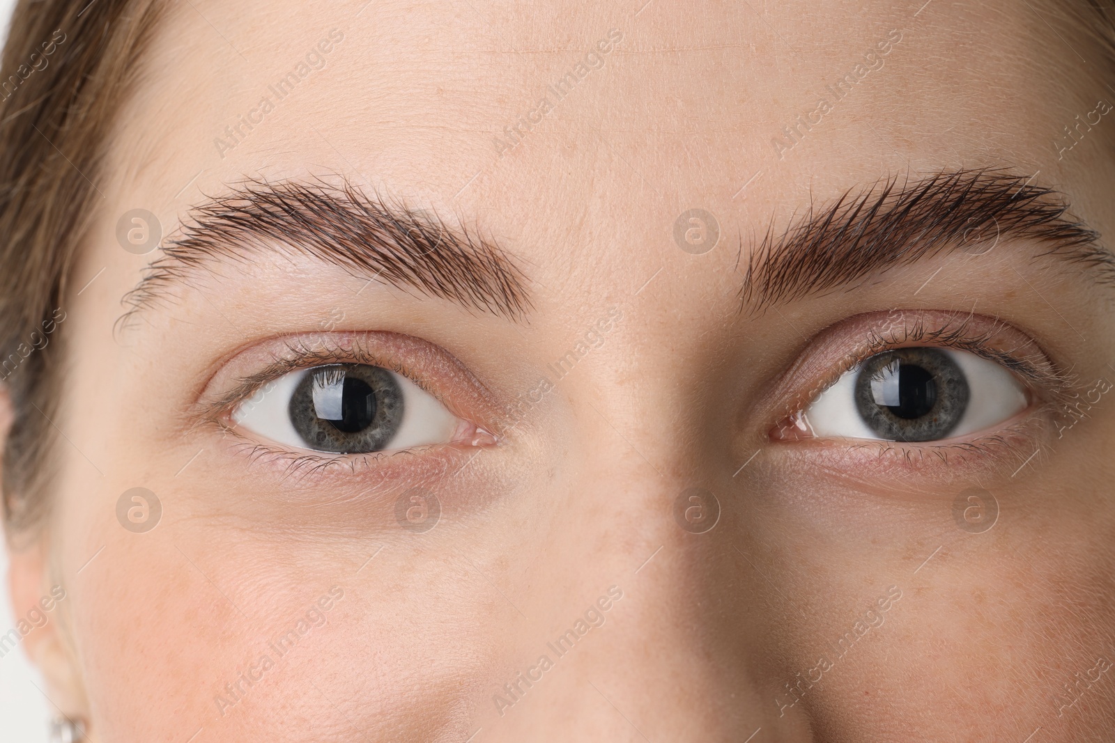 Photo of Young woman with beautiful eyes on light background, closeup