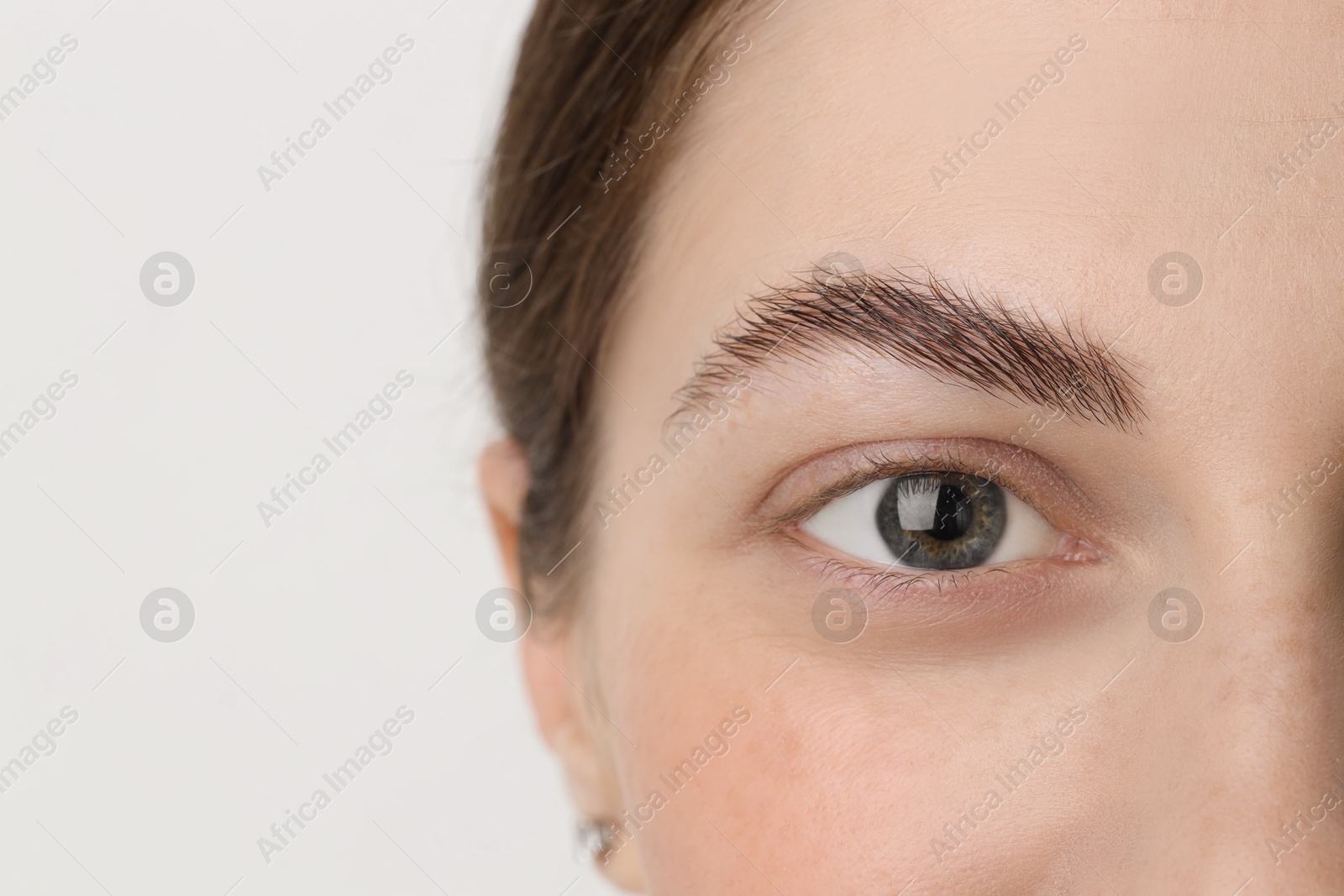 Photo of Young woman with beautiful eyes on light background, closeup