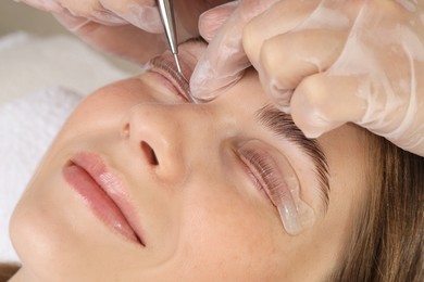 Photo of Eyelash lamination procedure. Esthetician sticking woman's lashes to pad in beauty salon, closeup