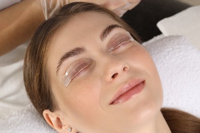 Photo of Woman undergoing eyelash laminating procedure in beauty salon, closeup