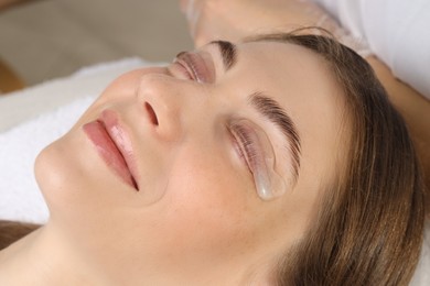 Photo of Woman undergoing eyelash laminating procedure in beauty salon, closeup