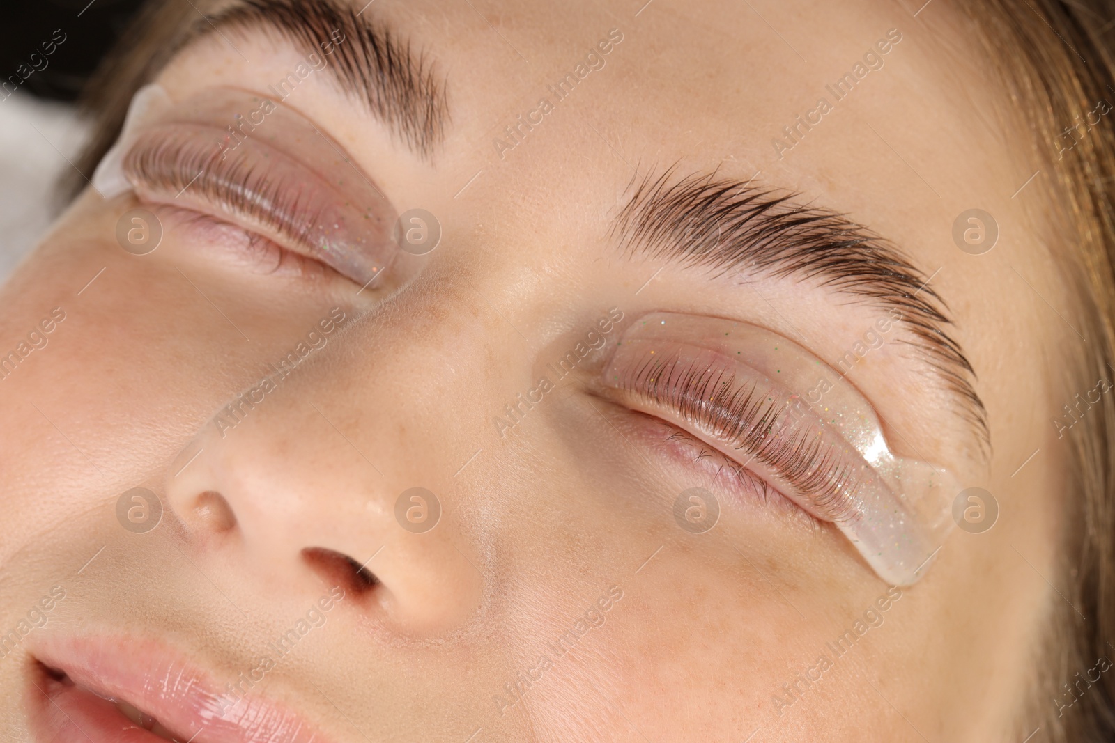 Photo of Woman undergoing eyelash laminating procedure in beauty salon, closeup