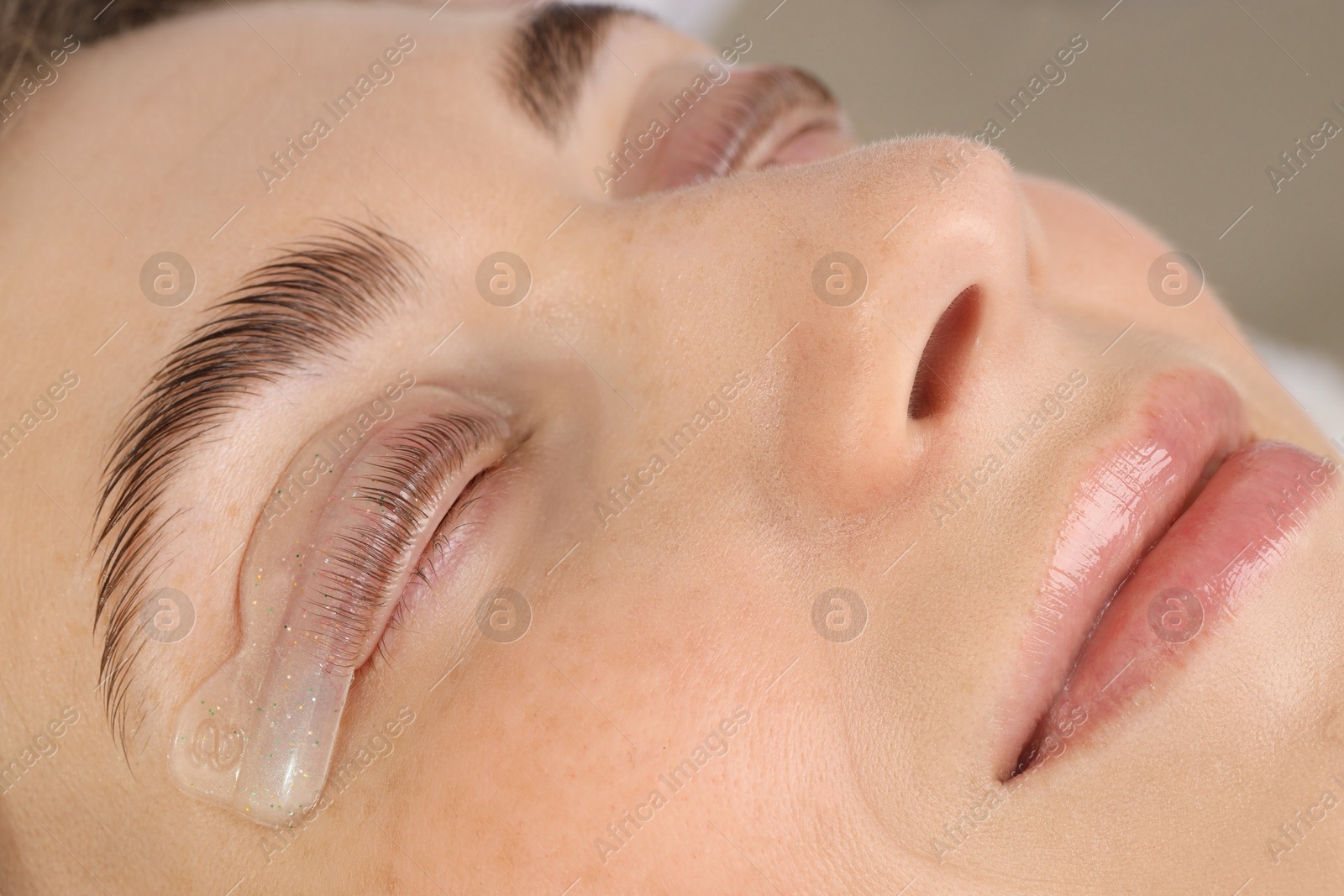 Photo of Woman undergoing eyelash laminating procedure in beauty salon, closeup