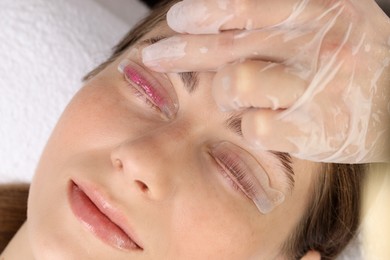 Photo of Woman undergoing eyelash laminating procedure in beauty salon, closeup