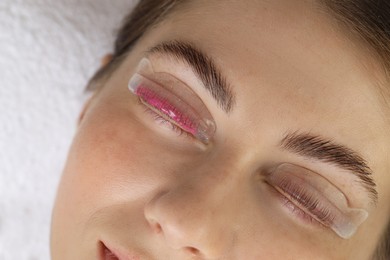 Photo of Woman undergoing eyelash laminating procedure in beauty salon, closeup