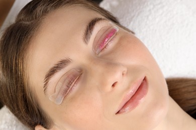 Photo of Woman undergoing eyelash laminating procedure in beauty salon, closeup