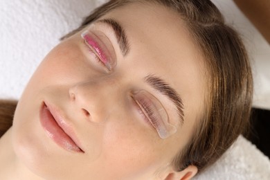 Photo of Woman undergoing eyelash laminating procedure in beauty salon, closeup