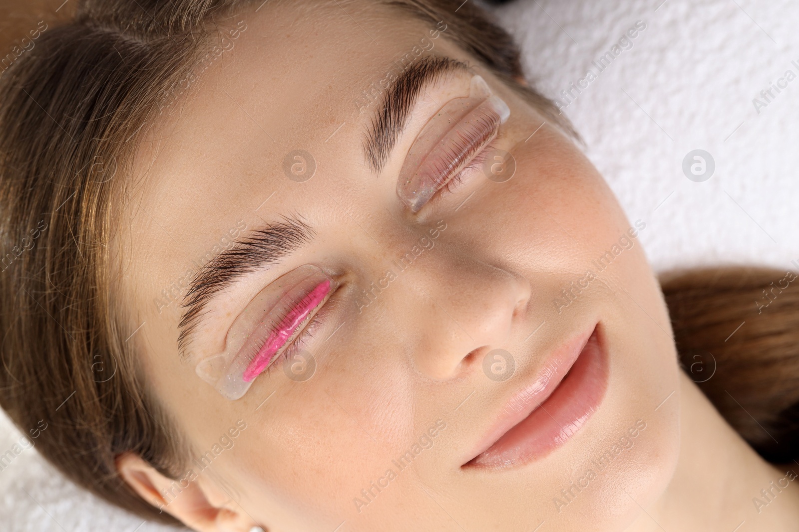 Photo of Woman undergoing eyelash laminating procedure in beauty salon, closeup