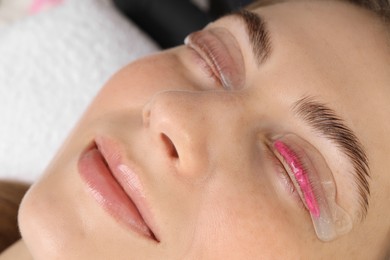 Photo of Woman undergoing eyelash laminating procedure in beauty salon, closeup